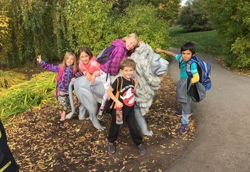 Children standing with statue of lion.